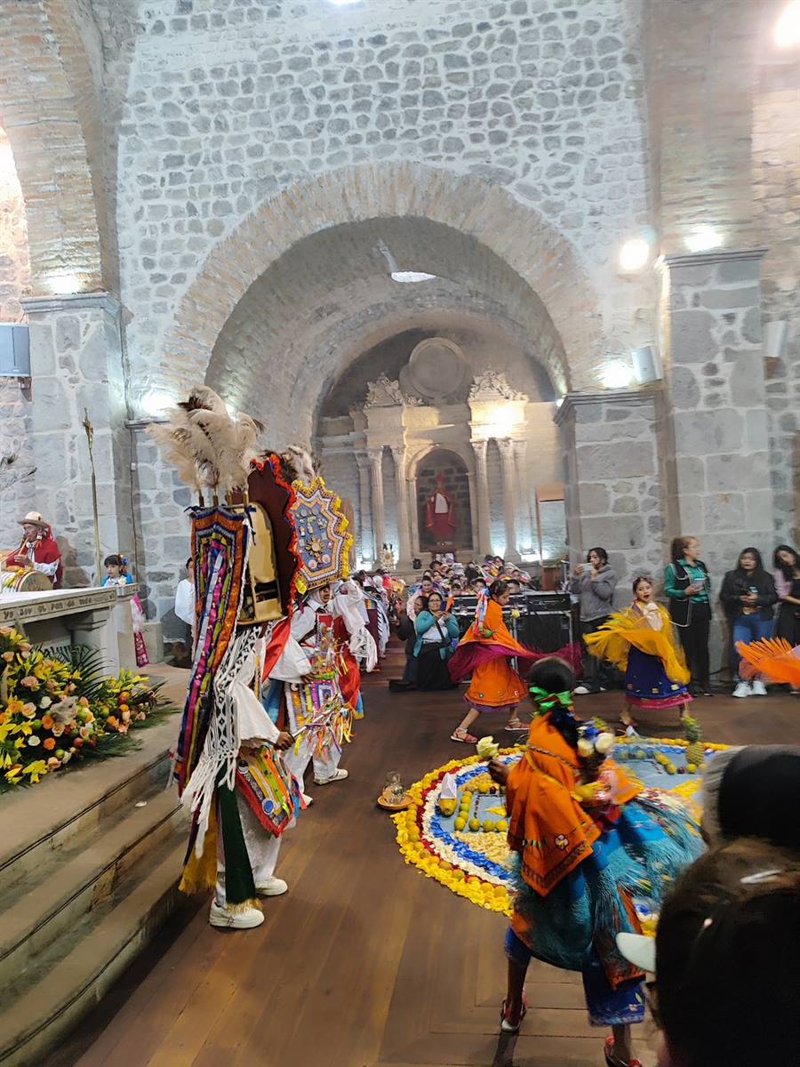 Fieles junto a la alfombra de flores y el Danzante